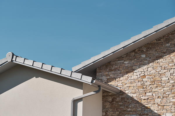 Combinaison de toiture tuiles plates gris clair, menuiseries gris clair parement pierres  - Constructeur maison Mètre Carré